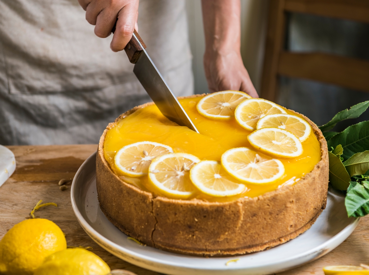 beautiful home baked lemon cheesecake being cut in half by a baker representing the work Cakeflix do.